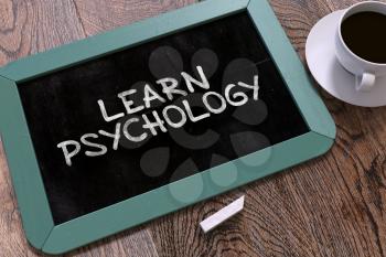 Handwritten Learn Psychology on a Blue Chalkboard. Top View Composition with Chalkboard and White Cup of Coffee. 3D Render.