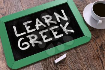 Learn Greek Handwritten by white Chalk on a Blackboard. Composition with Small Green Chalkboard and Cup of Coffee. Top View. 3D Render.