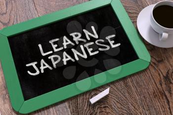 Handwritten Learn Japanese on a Green Chalkboard. Top View Composition with Chalkboard and White Cup of Coffee. 3D Render.