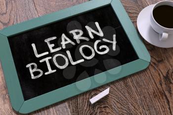 Learn Biology Handwritten by white Chalk on a Blackboard. Composition with Small Blue Chalkboard and Cup of Coffee. Top View. 3D Render.