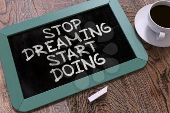 Handwritten Stop Dreaming Start Doing on a Blue Chalkboard. Top View Composition with Chalkboard and White Cup of Coffee. 3D Render.