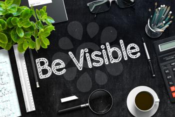 Be Visible Handwritten on Black Chalkboard. Top View of Black Office Desk with a Lot of Business and Office Supplies on It. 3d Rendering. Toned Image.