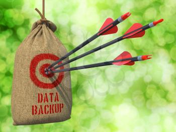 Data Backup - Three Arrows Hit in Red Target on a Hanging Sack on Green Bokeh Background.