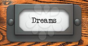 Dreams - Inscription on File Drawer Label on a Wooden Background.