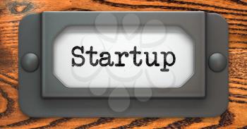 Startup - Inscription on File Drawer Label on a Wooden Background.