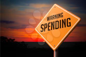 Spending on Warning Road Sign on Sunset Sky Background.