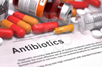 Antibiotics - Printed Diagnosis with Blurred Text. On Background of Medicaments Composition - Red Pills, Injections and Syringe.