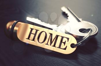 Keys and Golden Keyring with the Word Home over Black Wooden Table with Blur Effect. Toned Image.