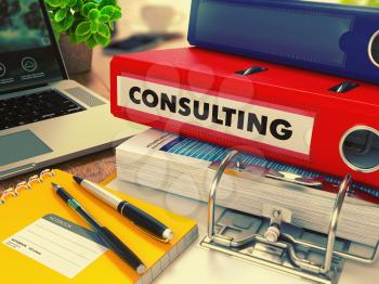 Red Office Folder with Inscription Consulting on Office Desktop with Office Supplies and Modern Laptop. Business Concept on Blurred Background. Toned Image.