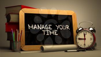 Handwritten Manage Your Time on a Chalkboard. Composition with Chalkboard and Stack of Books, Alarm Clock and Rolls of Paper on Blurred Background. Toned Image.