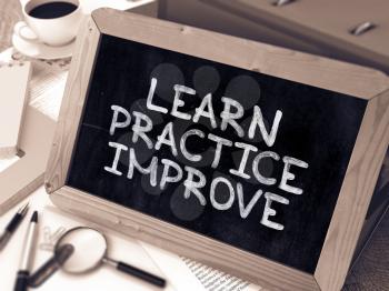 Learn, Practice, Improve. Handwritten by white Chalk on a Blackboard. Composition with Small Chalkboard on Working Table with Office Folders, Stationery, Reports. Blurred, Toned Image.