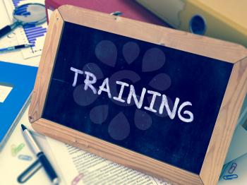 Handwritten Training on a Chalkboard. Composition with Chalkboard and Ring Binders, Office Supplies, Reports on Blurred Background. Toned Image.