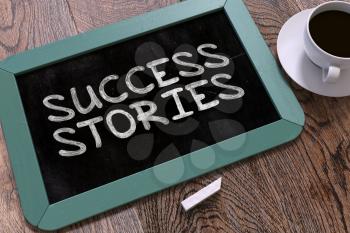 Success Stories Handwritten on Blue Chalkboard. Business Concept. Composition with Chalkboard and Cup of Coffee. Top View Image.