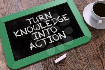 Turn Knowledge into Action - Green Chalkboard with Hand Drawn Motivational Quote and White Cup of Coffee on Wooden Table. Top View.