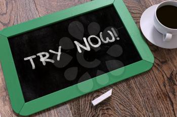 Try Now - Inspirational Quote Hand Drawn on Green Chalkboard on Wooden Table. Business Background. Top View.