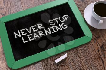 Never Stop Learning - Motivation Quote Handwritten on Green Chalkboard. Business Concept. Composition with Chalkboard and Cup of Coffee. Top View Image.