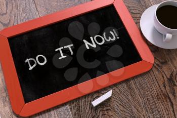 Handwritten Do It Now - Motivation Quote on a Red Chalkboard. Top View Composition with Chalkboard and White Cup of Coffee.