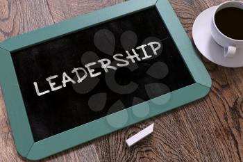 Leadership - Blue Chalkboard with Hand Drawn Text and White Cup of Coffee on Wooden Table. Top View.