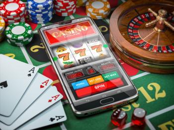 Casino online. Smartphone or mobile phone, slot machine, dice, cards and roulette on a green table in casino. 3d illustration