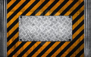 Metal panel on black and yellow striped caution pattern of industrial concrete wall