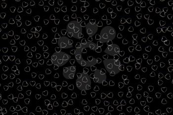 Valentine's Day abstract 3D illustration pattern with black hearts on dark background surrounded by white glow.