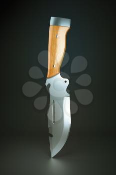Hunting knife with wooden handle over grey background