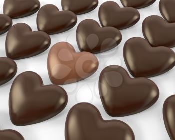 Heart shaped milk chocolate candy between dark ones, isolated on white background