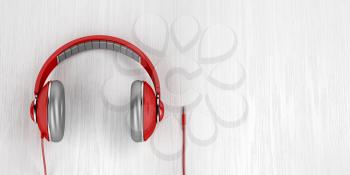 Red over-ear headphones with 3.5mm headphone connector on wood background