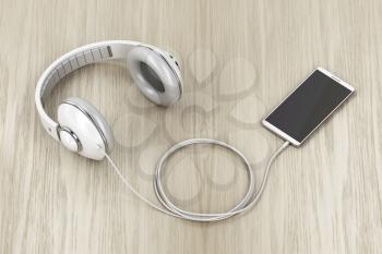 Big wired headphones and smartphone with blank display on wood table