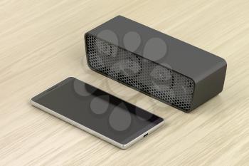 Black smartphone and portable wireless speaker on wood table