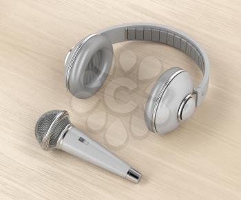Grey wireless microphone and headphones on wood background