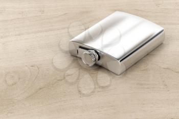 Silver hip flask on wood table