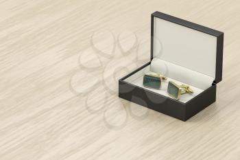 Box with golden cufflinks on wooden table