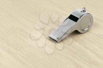 Silver referee whistle on wood desk