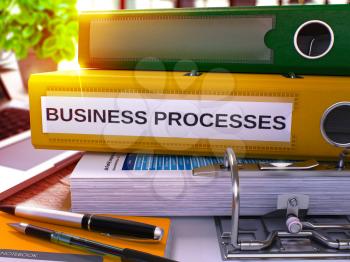 Business Processes - Yellow Office Folder on Background of Working Table with Stationery and Laptop. Business Processes Business Concept on Blurred Background. Business Processes Toned Image. 3D