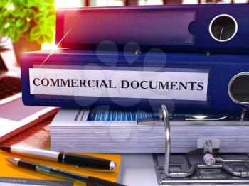 Blue Ring Binder with Inscription Commercial Documents on Background of Working Table with Office Supplies and Laptop. Commercial Documents Business Concept on Blurred Background. 3D Render.