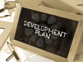 Development Plan Handwritten by White Chalk on a Blackboard. Composition with Small Chalkboard on Background of Working Table with Office Folders, Stationery, Reports. Blurred, Toned Image. 3D Render.