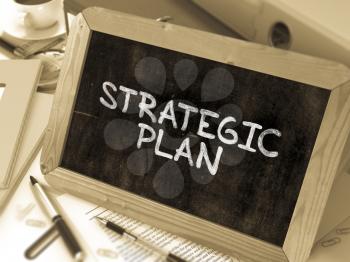 Strategic Plan Handwritten by white Chalk on a Blackboard. Composition with Small Chalkboard on Background of Working Table with Office Folders, Stationery, Reports. Blurred, Toned Image. 3D Render.