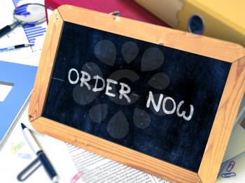 Handwritten Order Now on a Chalkboard. Composition with Chalkboard and Ring Binders, Office Supplies, Reports on Blurred Background. Toned Image. 3D Render.