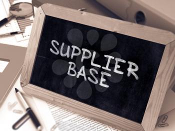 Supplier Base Handwritten on Chalkboard. Composition with Small Chalkboard on Background of Working Table with Ring Binders, Office Supplies, Reports. Blurred Background. Toned Image. 3D Render.