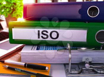 Green Ring Binder with Inscription ISO - International Organization Standardization - on Blurred Background of Working Table with Office Supplies and Laptop. ISO - Toned Illustration. 3D Render.