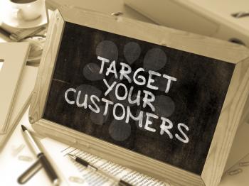 Handwritten Target Your Customers on a Chalkboard. Composition with Chalkboard and Ring Binders, Office Supplies, Reports on Blurred Background. Toned Image. 3D Render.