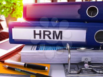Blue Office Folder with Inscription HRM - Human Resources Management - on Office Desktop with Office Supplies and Modern Laptop. HRM Business Concept on Blurred Background. HRM - Toned Image. 3D.