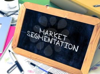 Market Segmentation Handwritten by White Chalk on a Blackboard. Composition with Small Chalkboard on Background of Working Table with Office Folders, Stationery, Reports. Blurred Background. 