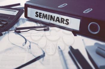 Seminars - Office Folder on Background of Working Table with Stationery, Glasses, Reports. Business Concept on Blurred Background. Toned Image.