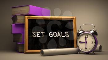 Set Goals - Chalkboard with Hand Drawn Text, Stack of Books, Alarm Clock and Rolls of Paper on Blurred Background. Toned Image. 3D Render.
