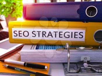 SEO - Search Engine Optimization - Strategies - Yellow Office Folder on Blurred Background of Working Table with Stationery and Laptop. Business Concept. SEO Strategies Toned Image. 3D.