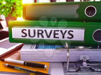 Surveys - Green Office Folder on Background of Working Table with Stationery and Laptop. Surveys Business Concept on Blurred Background. Surveys Toned Image. 3D.