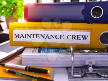 Yellow Ring Binder with Inscription Maintenance Crew on Background of Working Table with Office Supplies and Laptop. Maintenance Crew Business Concept on Blurred Background. 3D Render.