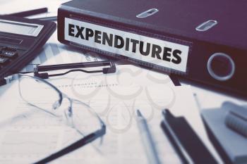 Ring Binder with inscription Expenditures on Background of Working Table with Office Supplies, Glasses, Reports. Toned Illustration. Business Concept on Blurred Background.